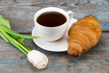 tulips and coffee cup and croissant on wooden table. Top view with copy space