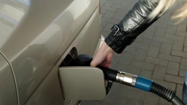 Woman driver at the gas station. A person pours gasoline into the car.