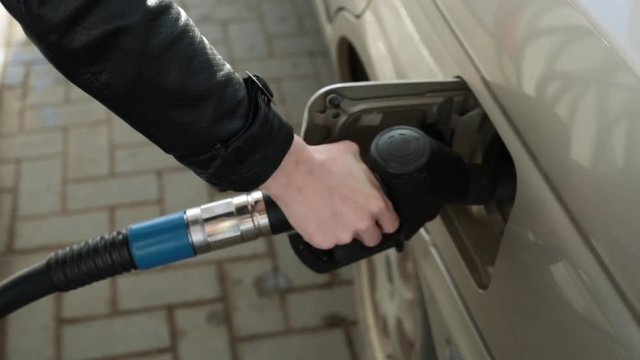 A person pours gasoline into the car. Woman driver at the gas station.