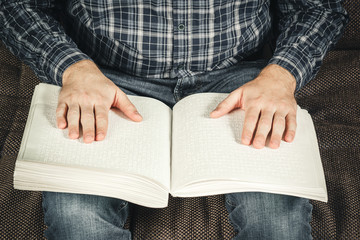 The blind man was reading a book written on Braille. Touch your finger on the braille code. A book...