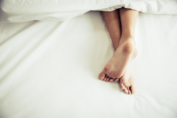 Barefoot of human on bed in morning. Single and Working people concept. Lazy day and Happiness home theme.