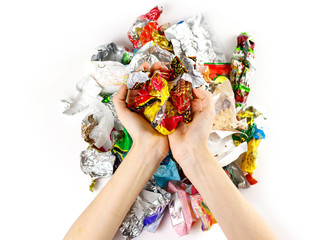 Hands holding a bunch of candy wrappers on a white background. Closeup