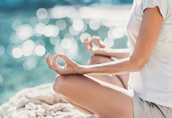 Young woman practicing yoga near the sea in summer. Harmony and meditation concept. Healthy lifestyle, relaxation, self care, mindfulness concept. Enjoying life and summer fun