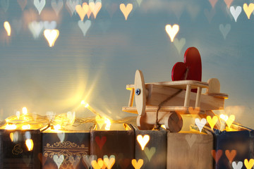 Valentine's day background. Wooden toy plane with heart over old books.