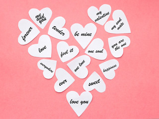 Big heart from paper cards with words about love and feelings. Pink paper background. Valentine's day concept.
