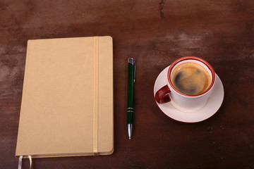 Notebook with pen and coffee cup on wooden background, business concept