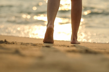 leg a girl walking on the beach with sunset light by walk barefoot