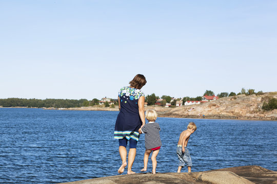 Rear view of mother and children near waterside