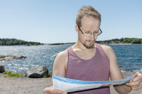 Man reading map near lakeside