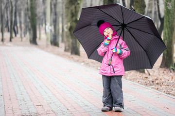 Little  girl walking under umbrella in a park