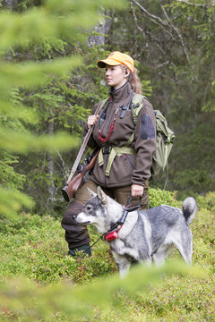 Female hunter in forest with dog