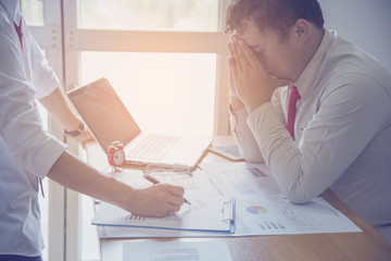 business, people, paperwork and deadline concept - stressed businessman with papers and charts sitting at table in office