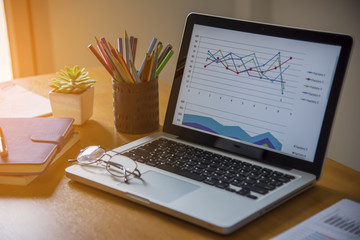 Laptop with financial documents on wooden table