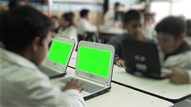 Primary Students Using Laptops Green Screen in Classroom. You can replace green screen with the footage or picture you want with “Keying” effect in AE (check out tutorials on YouTube). 