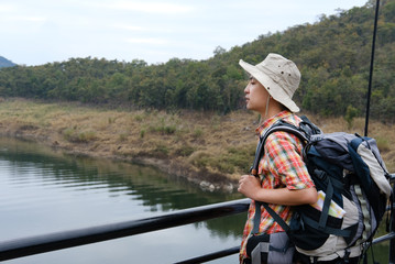 traveler man with backpack travel at forest & lake. tourist backpacker enjoying view. lifestyle, summer vacation concept