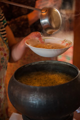 Pouring soup from retro russian authenticity cast-iron dishes