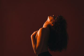Side view of topless woman standing against red background