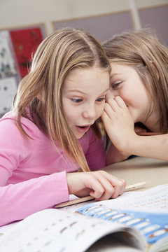 Young female students gossiping in class