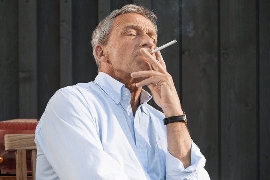 Senior man wearing shirt smoking cigarette
