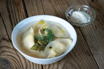 dumplings with broth in the bowl on wooden background
