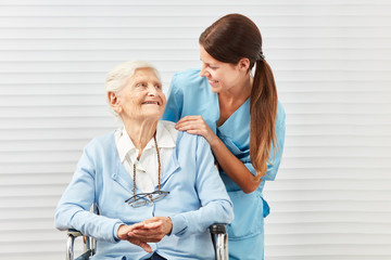 Lächelnde Seniorin im Rollstuhl und Pflegerin