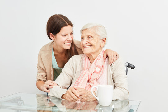 Pflegedienst Frau umarmt Seniorin beim Hausbesuch