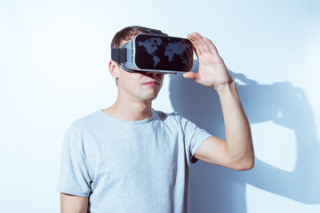 Young man wearing virtual reality goggles in modern coworking studio. Smartphone using with VR headset. Horizontal