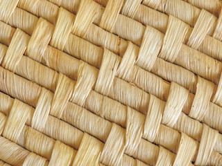 Close up of natural woven mat showing detail of the woven pattern. Dried leaves are used to create the design. Background texture.