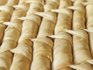 Close up rows of natural woven basketry showing detail of the woven pattern. Dried leaves are used to create the design. Background texture.
