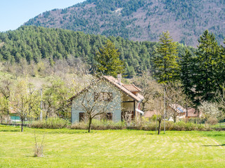 Buildings of house in Chichilianne town, small town in valley, countryside of France, under clear blue sky in spring season, with unique mountains in background