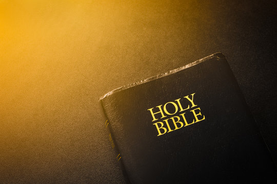 Holy Bible on black with light flare.