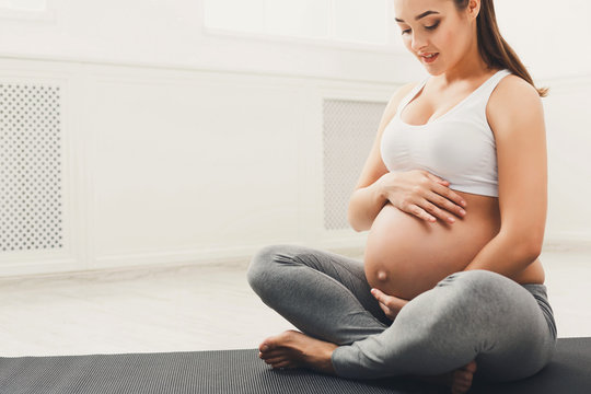 Pregnant woman caressing her belly at home