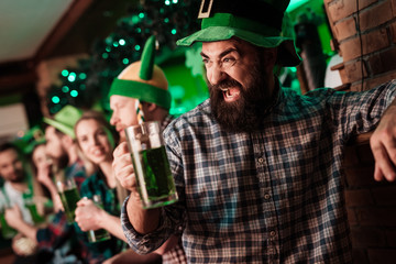The guy in the cap of the leprechaun is drinking beer.