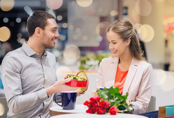 happy couple with present and flowers in mall