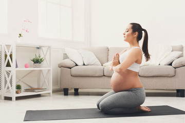 Fototapeta na wymiar Happy pregnant woman training yoga in hero pose