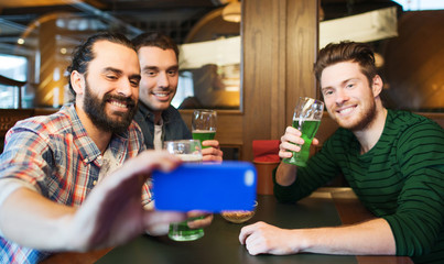 friends taking selfie with green beer at pub