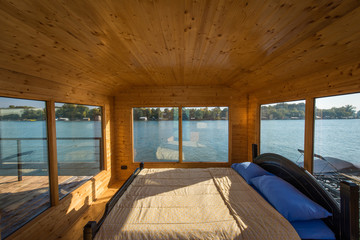 Luxury double bed in wooden bedroom by river with big windows
