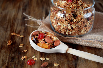 Granola in a glass jar and a wooden spoon. Rustic style