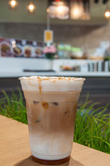 Gold caramel topping on white cream in coffee cup with green grass background.