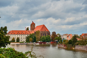 Fototapeta na wymiar Wroclaw Old Town. Cathedral Island (Ostrow Tumski) is the oldest part of the city at the sunset. Blessed Virgin Mary Church on Odra River Island Piasek and Odra Tumski bridge (Tumski Most).