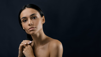 Beautiful woman holding her black hair, studio portrait