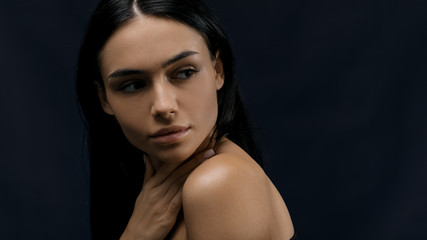 Portrait of a young beautiful woman with black hair looking away, studio shot