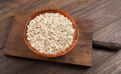 Bowl with oats on wooden table. Closeup