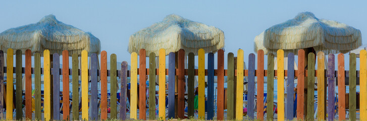 Fototapeta premium colorful fence on the beach with retro umbrellas. Vintage tone color style.