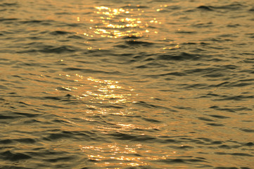 Gold and Gray shimmering surface of a sea water in during the sunset, Light is on the surface of water background.