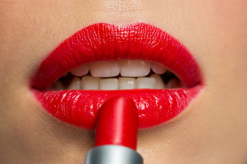 close up of woman applying red lipstick to lips