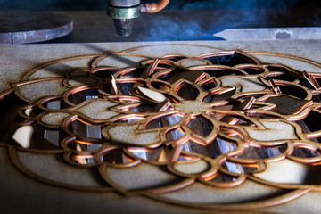 The laser cuts out a tree in the form of a mandala 