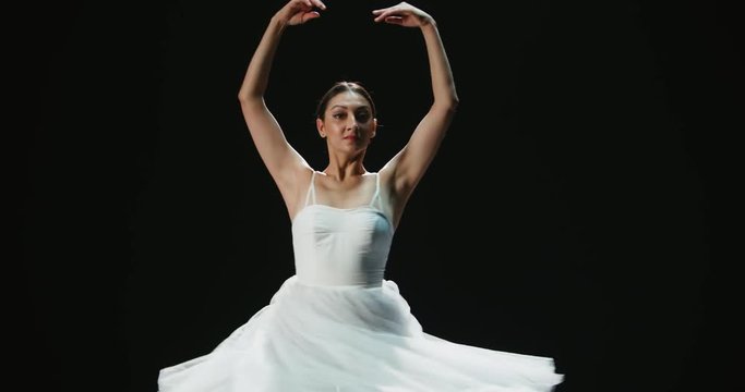 4K video footage beautiful pirouettes girl ballet dancer dancing on black background, slow motion