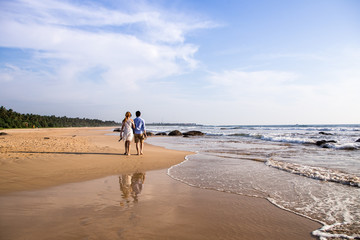 Back view of happy young couple walking on a deserted tropical beach. toning photo