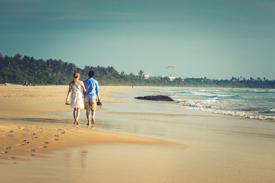 Back view of happy young couple walking on a deserted tropical beach. toning photo